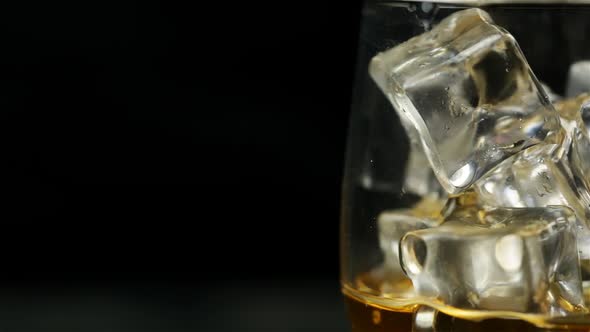 Whiskey Is Poured Into An Ice Glass Close To The Right Side Of The Screen