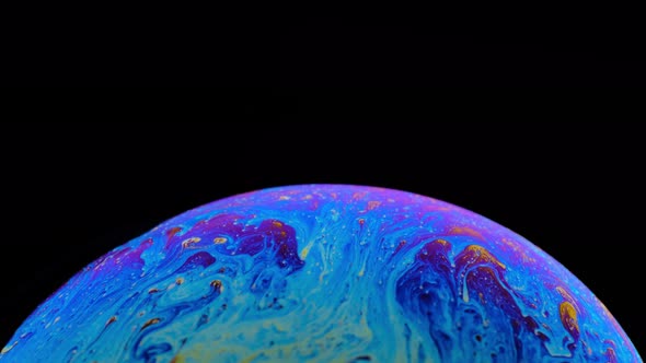 Multi-colored Iris of a Soap Bubble in Motion. Black Background alt