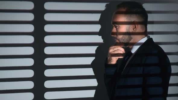 Pensive Business Male in Suit Thinking Brainstorming Analyzing Job at Gray Room with Jalousie Shadow alt