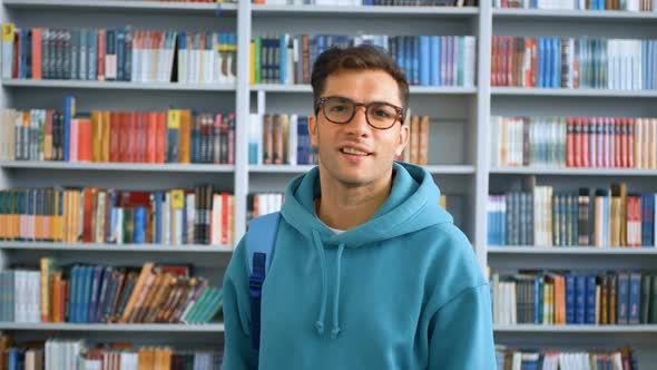 Closeup Portrait of a Young Attractive Guy Student on the Background of Bookshelves in the