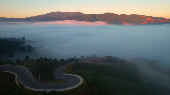 4K High mountain road in fog. Tropical forest with smoke and fog. Aerial view from drone alt