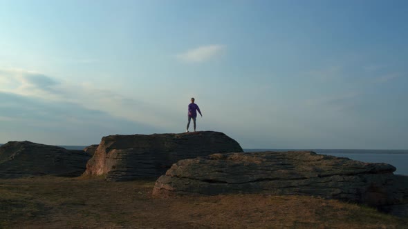 A Girl is Doing Fitness on a Hill on the Lake Shore