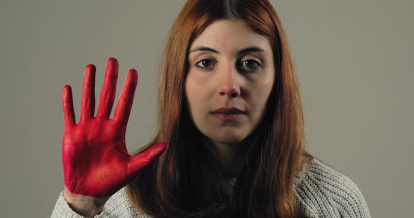 Sad Girl Raises Her Hand Painted Red to Stop and Protest Against Violence alt