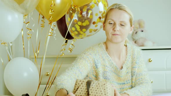 Mom Wraps a Box with a Gift in Wrapping Paper alt