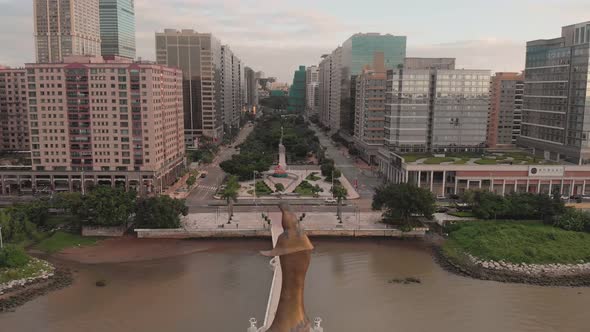Rising aerial shot behind Kun Iam golden statue in NAPE business area in Macau alt