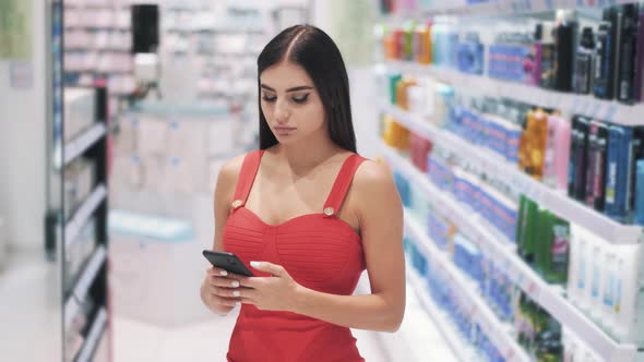 Woman Chatting in Social Networks Using Smartphone While Shopping alt