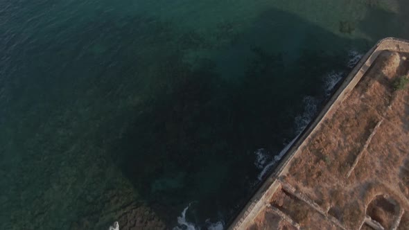 Resort exotic white city of Chania in Crete, water to city tilting up drone view alt