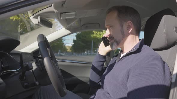 A Middleaged Handsome Caucasian Man Talks on a Smartphone in His Car  Closeup