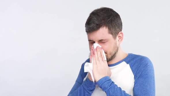 Sick Man with Symptoms of Flu Sneezing Nose in White Tissue Isolated on Grey Background alt