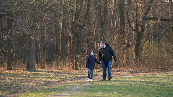 Dad and daughter walk in the spring Park in medical masks