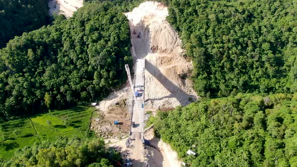 Heavy equipment building bridge over valley in Indonesia forest area, aerial view alt