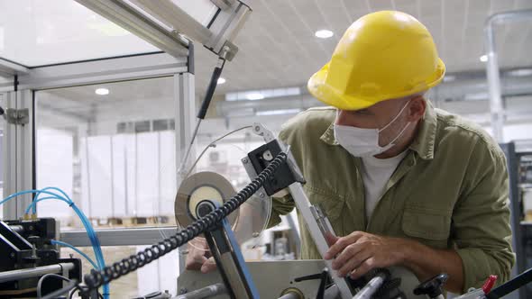Thoughtful Man in Protective Helmet Looking at Mechanism alt