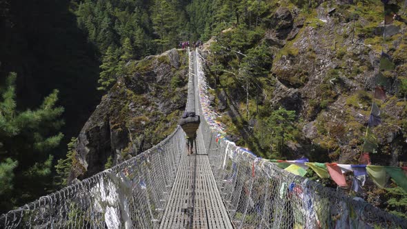 Porter Is Walking on Suspension Bridge in Khumbu. Himalaya, Nepal alt
