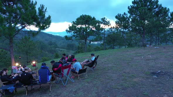 Group of friends sitting outside enjoying nature with mountain view under beautiful blue evening sky