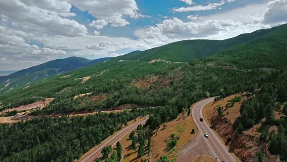 Aerial video of the road through dense green forest on mountain slopes in Wyoming, USA alt