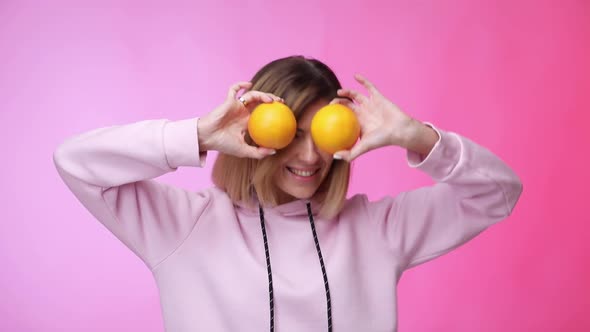 Woman in Casual Pink Clothes Holding Oranges and Dancing