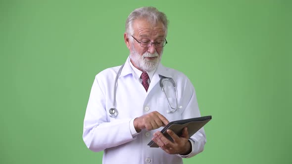 Handsome Senior Bearded Man Doctor Against Green Background alt