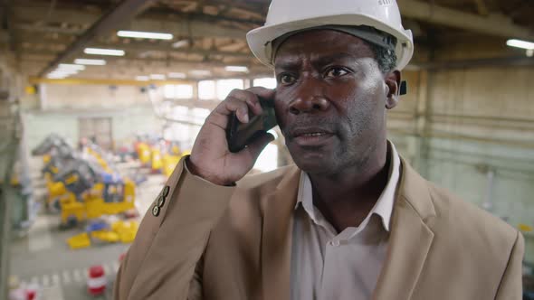 African American Engineer Speaking on Mobile Phone in Factory alt