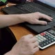 The Accountant at Home at the Computer Counts the Numbers on the Calculator and Transfers the Amount - VideoHive Item for Sale