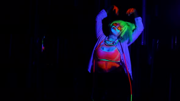 Gogo Dancer Woman is Moving in Nightclub Fluorescent Makeup and Wig in UV Lights on Dance Floor alt