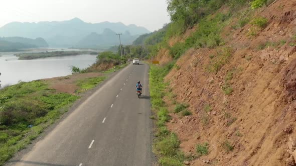 Aerial view of Motorcyclist on road next to Mekong River, Laos  alt