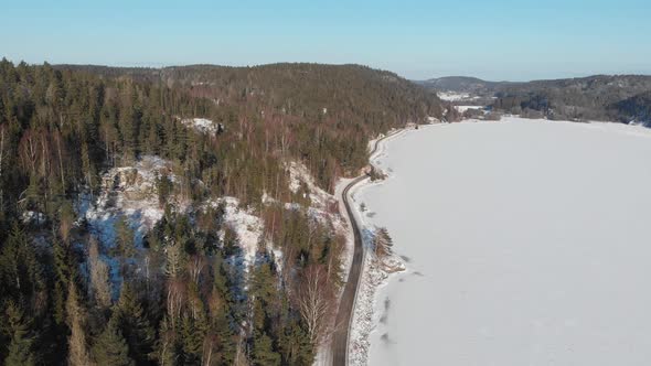 Road Along Shoreline Frozen Lake with Snow Aerial Pull Back