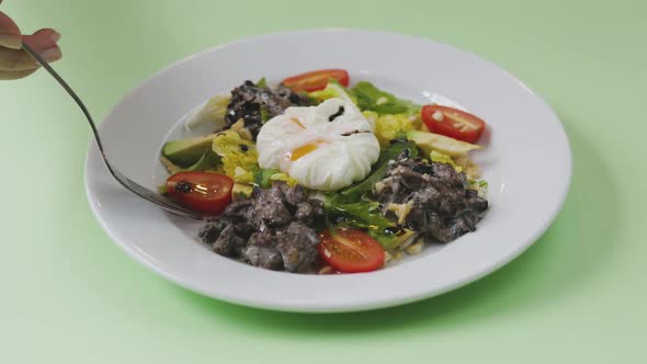 Vegetable Salad and Poached Eggs. Plate with Salad on a Green Background. Woman Eating Salad with