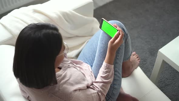 Woman Sits on Sofa and Holds Smartphone Screen in Front of at Home Spbd alt