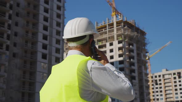 Building Inspector Making Call at Construction Site alt