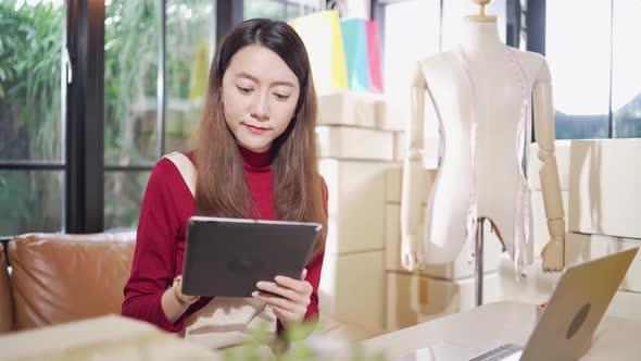 Asian female shop owner checking customer order on tablet alt