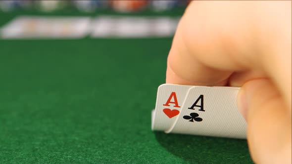 POKER: The player's hand opens and looks his cards on a table