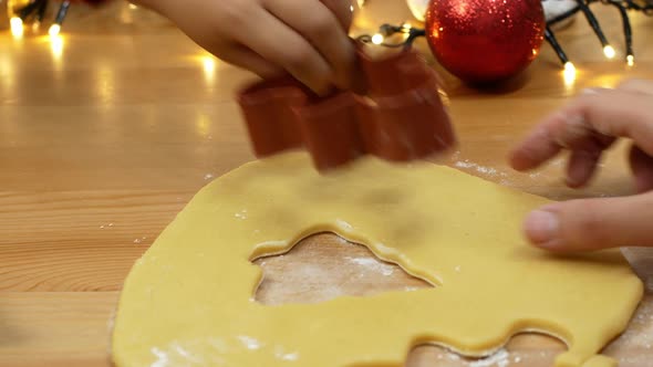 Mom and daughter make gingerbread in the form of a man and a Christmas tree. alt