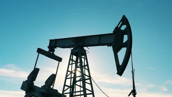 Slow Motion of Oil Pumpjack at Oil Field Against Blue Sky alt