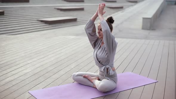 Front View of Meditating Woman Putting Hands in Namaste Mudra Posture Sitting in Lotus Pose in alt