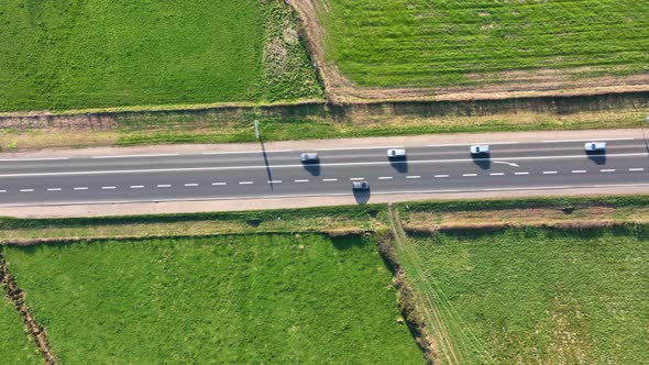 Aerial View of Intercity Road Between Green Agricultural Fields with Fast Driving Cars alt