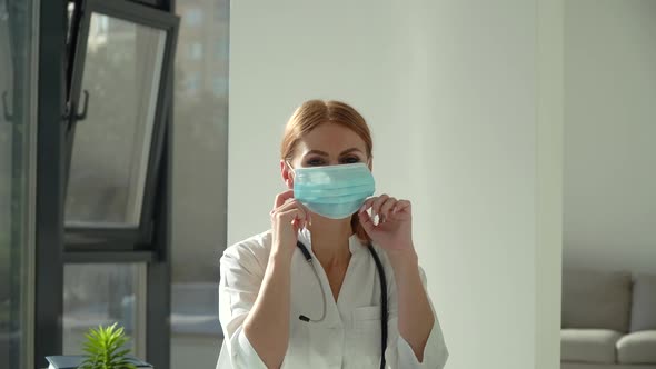 Female Doctor Puts on Medical Mask in Clinic. Health Protection Coronavirus Concept alt
