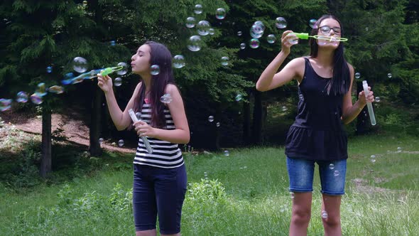 Teenage Girls Blowing Soap Bubbles in Summer Time 