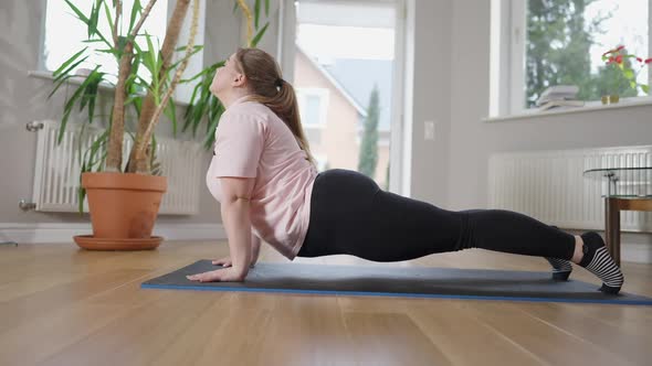 Side View of Flexible Plussize Caucasian Woman in Snake Pose on Exercise Mat alt