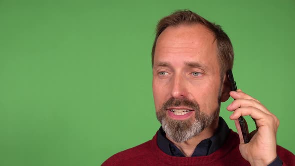 A Middleaged Handsome Caucasian Man Talks on a Smartphone  Closeup  Green Screen Background