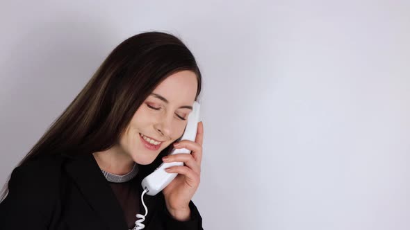 A young woman in a business suit answering the telephone and flirting romantically alt