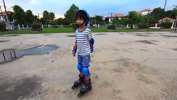 Asian Child Riding On Rollers In The Summer In The Park alt