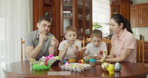 Happy Family Painting Easter Eggs in Kitchen alt