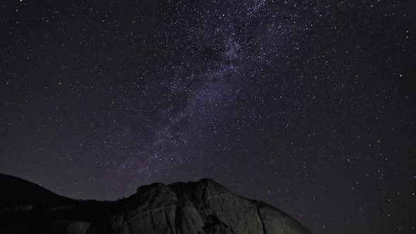 Shimmering Stars and the Milky Way in the Night Sky above High Mountain Rocks alt