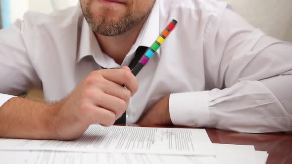 Man With A Beard In The Office With A Tie Works, Fills Out Documents With A Pen With A Rainbow Lgbt