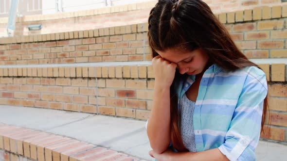 Depressed girl sitting on stairs in campus alt