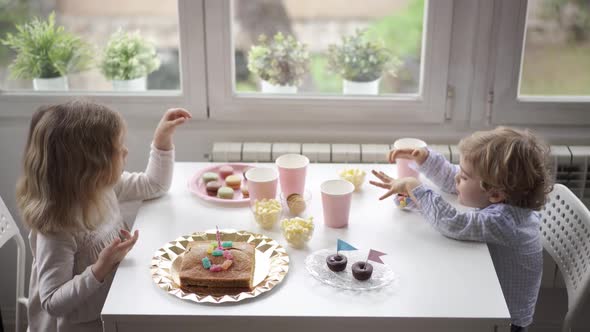 Little kids sitting at table near window in living room
