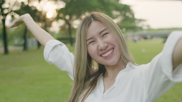 Smiling Asian females taking selfie photos on smartphones.