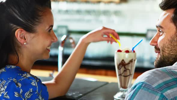 Happy couple interacting while having milkshake alt