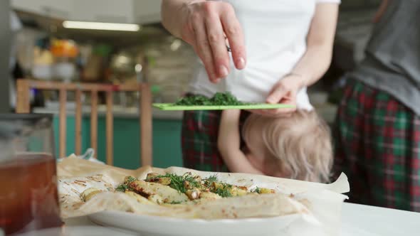 Cute Kid Disturbing Mother Preparing Appetizing Dish in Kitchen