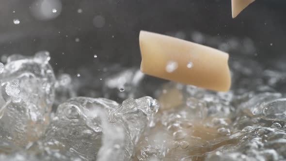 Throwing penne pasta in boiling water. Slow Motion. alt